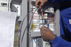 Proplant PCE technician wiring an industrial electrical control panel during assembly and commissioning.